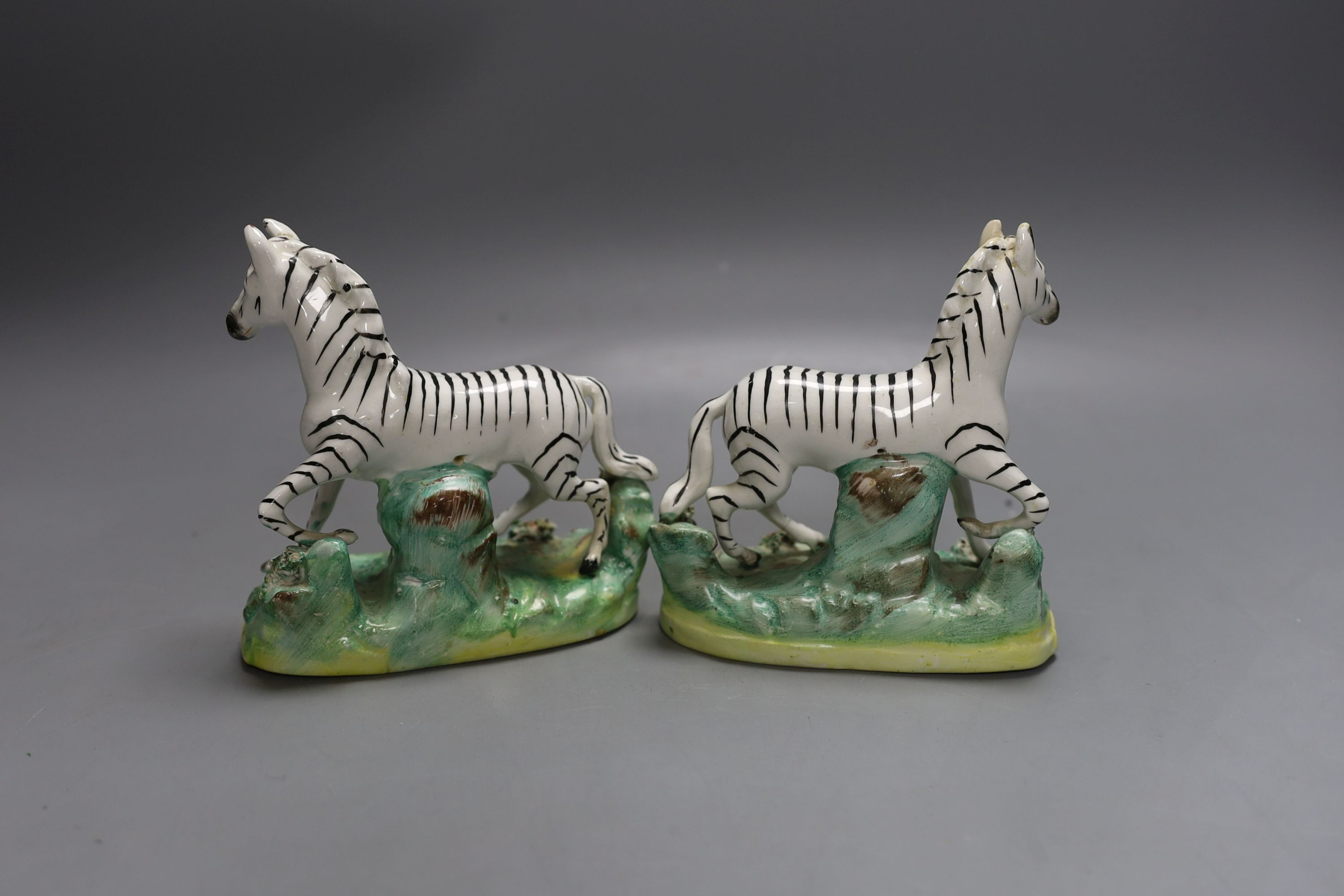 A pair of Victorian Staffordshire models of zebra, standing on an oval tree stump bases 12cm long